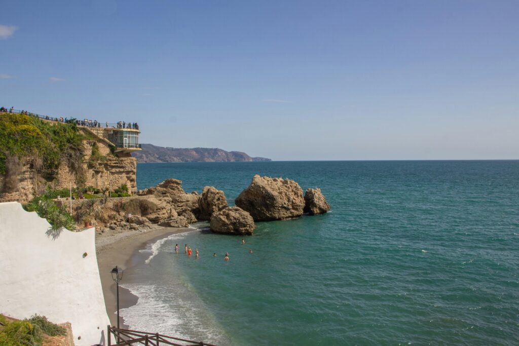 Panoramic view of the beach in Nerja with the iconic Balcon de Europa viewpoint perched on the cliffs.