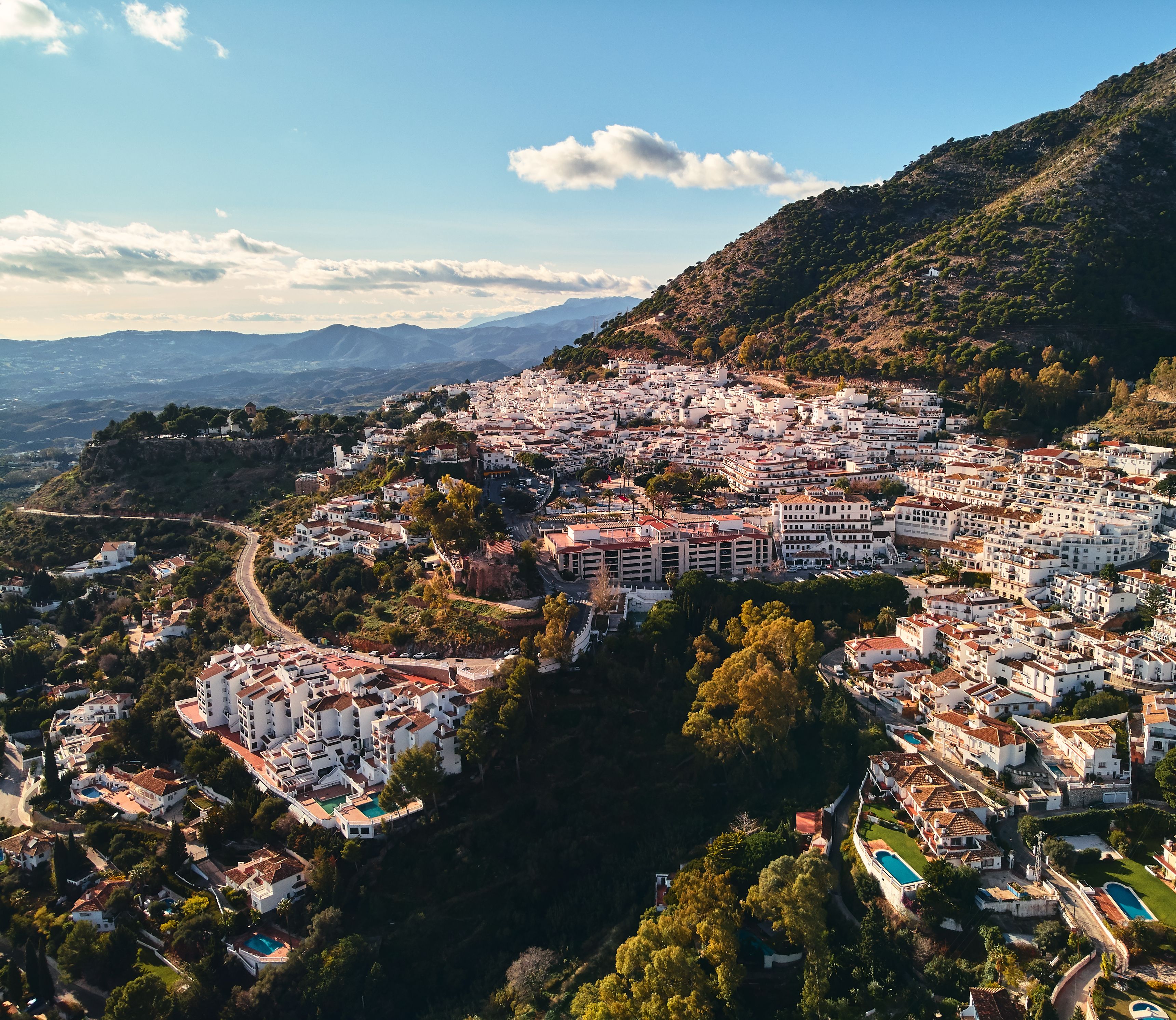 Aerial drone view of the Mijas municipality whitewashed houses nestled in the Andalusian mountains.