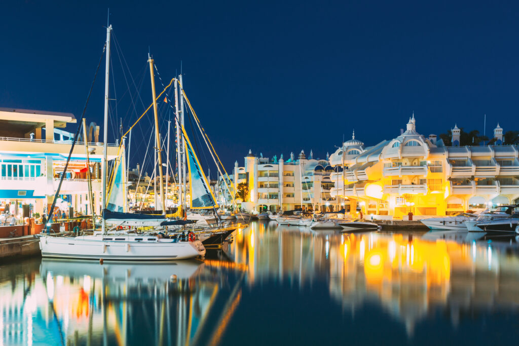 Floating Andalusian-style apartments and yachts illuminated at night in Puerto Marina, Benalmadena, Spain.