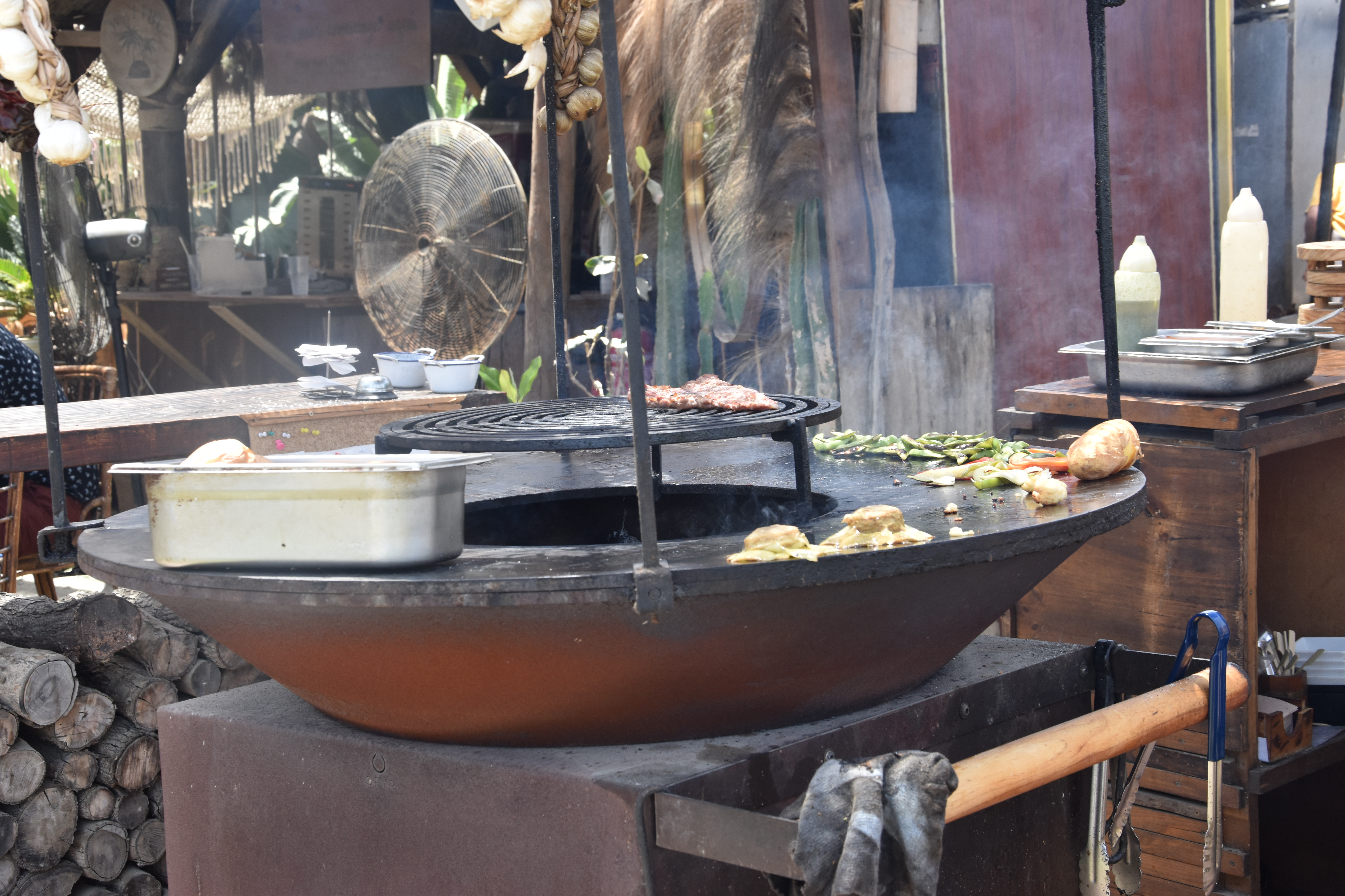 Close-up of fresh fish being grilled on skewers over an open olive wood fire pit at a traditional beachfront chiringuito restaurant on the Costa del Sol in Malaga.