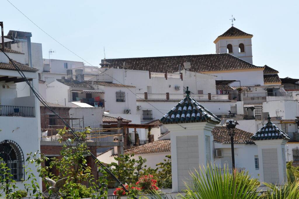 Elevated view of traditional white houses and terracotta tiled roofs in the authentic Andalusian village of Iznate, Axarquía region.